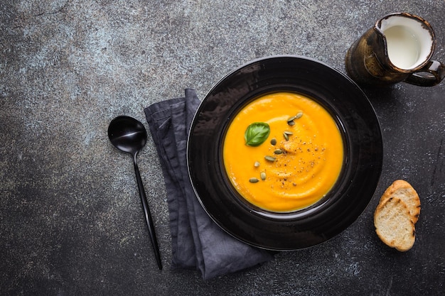 Vegetarische Herbstkürbiscremesuppe mit Kernen auf dunklem Hintergrund, Draufsicht