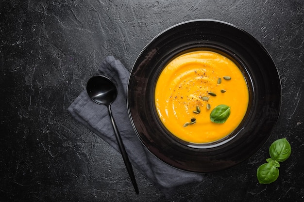 Vegetarische Herbstkürbiscremesuppe mit Kernen auf dunklem Hintergrund, Draufsicht