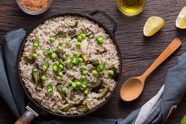 Vegetarische Paella mit grünen Erbsen und Avocado in einer Pfanne serviert