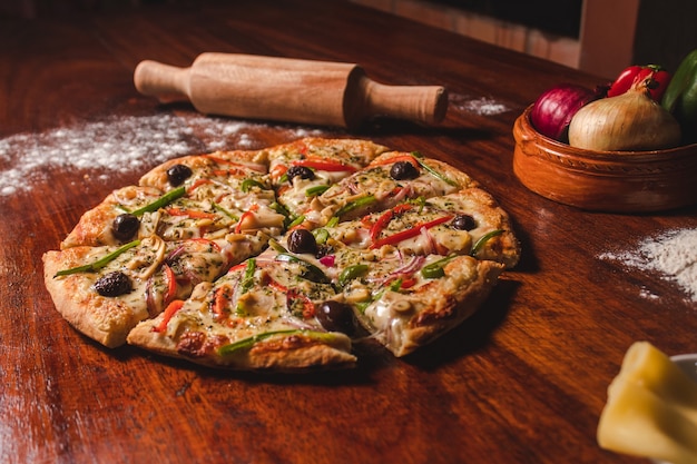 Vegetarische Pizza in Stücke geschnitten auf einem Holztisch.