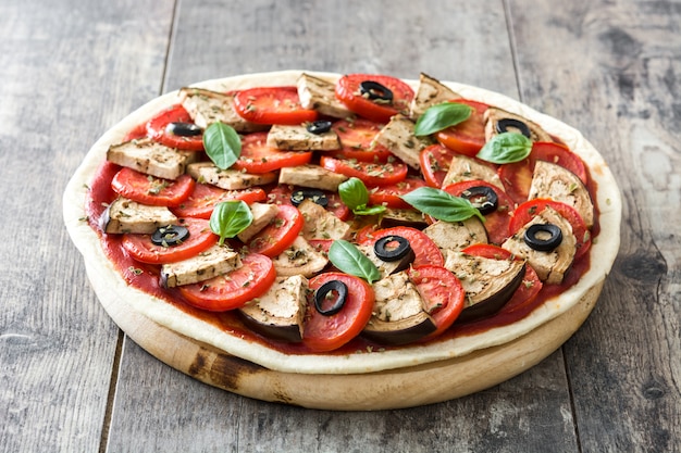 Vegetarische Pizza mit Auberginen, Tomaten, schwarzen Oliven, Oregano und Basilikum