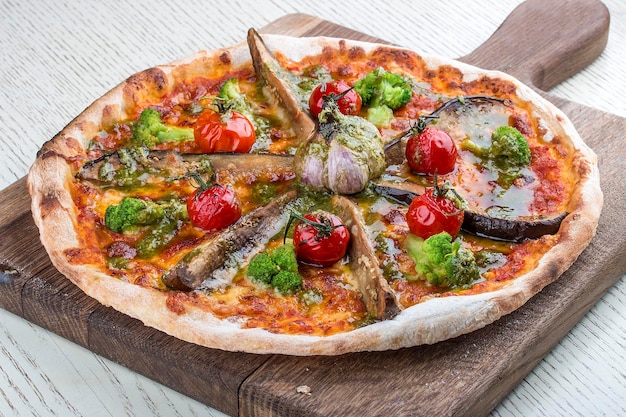 Vegetarische Pizza mit Auberginenbrokkoli und Knoblauch auf einem Holzbrett