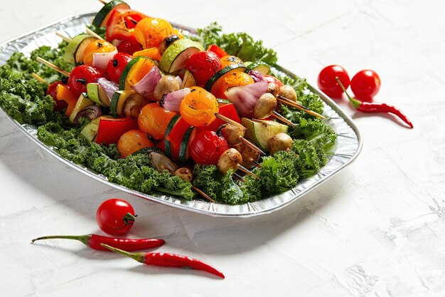 Vegetarische Spieße mit trockenen Kräutern auf Holzspießen von Zucchini-Tomaten-Zwiebel-Pilzen auf einem Teller.