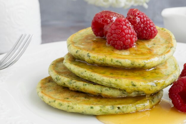 Vegetarische Spinatpfannkuchen mit Himbeeren und Honig.