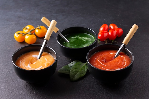 Vegetarische Tomaten- und Spinatsuppen auf schwarzem Hintergrund