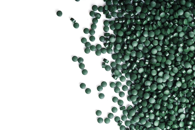 Vegetarische Vitamine aus Spirulina sind auf weißem Hintergrund mit freiem Platz verstreut