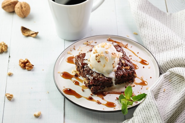 Vegetarischer Brownie mit Eis auf der Oberseite, serviert mit einer Tasse schwarzem Kaffee