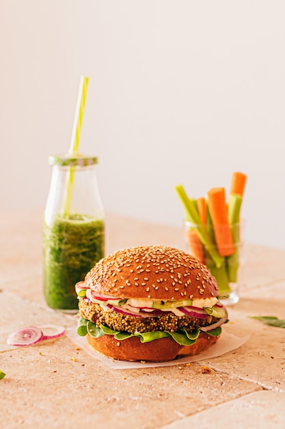 Vegetarischer Burger mit einer Flasche grünem Smoothie und Karotte mit Sellerie in einem Glas