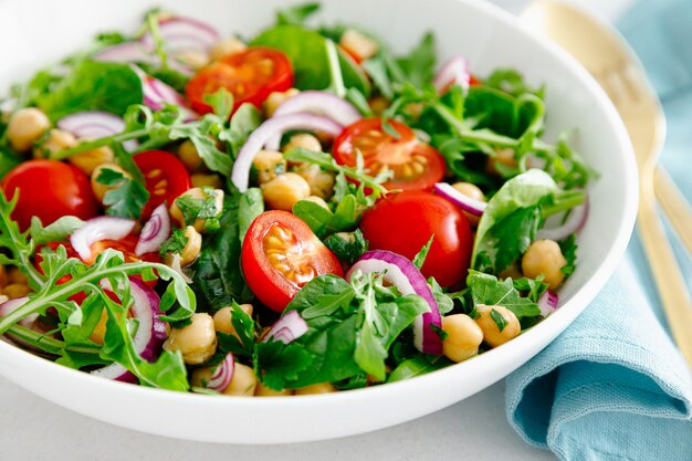 Vegetarischer Kichererbsensalat mit Tomaten, Rucola, Petersilie, Spinat und roten Zwiebeln Gesunde Ernährung