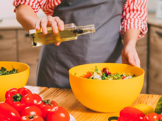 Vegetarischer Lebensstil Schnappschuss einer Frau, die Dressing-Gemüsesalat mit Bio-Olivenöl kocht