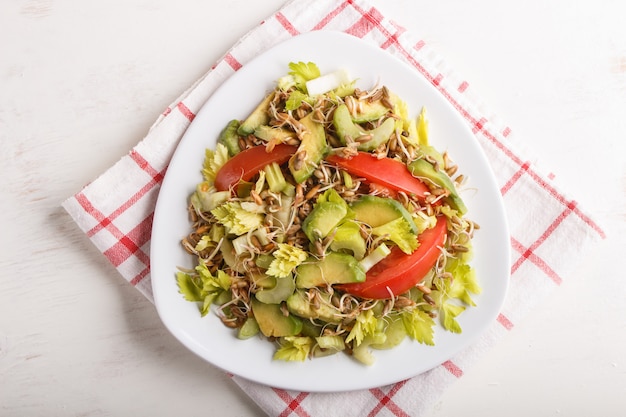 Vegetarischer Salat des Selleries, des gekeimten Roggens, der Tomaten und der Avocado auf Leinentischdecke, Draufsicht.