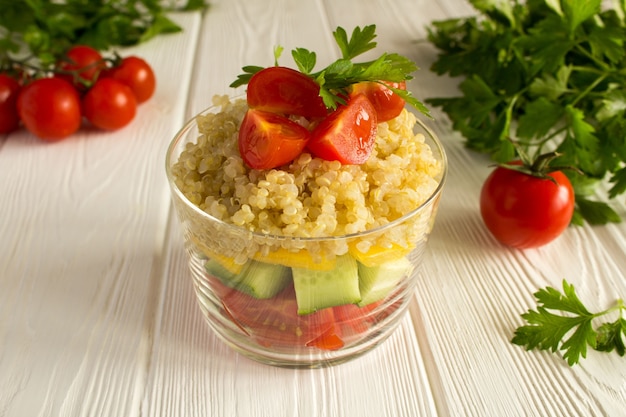 Vegetarischer Salat mit Gemüse und Quinoa auf dem weißen Holz