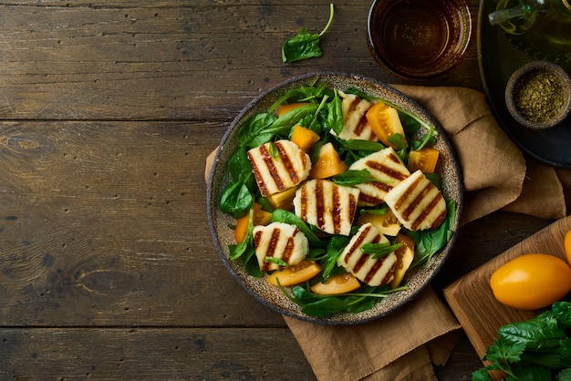 Vegetarischer Salat mit zirkassischem Halloumi-Käse-Tomaten-Spinat und Nüssen auf Holzuntergrund