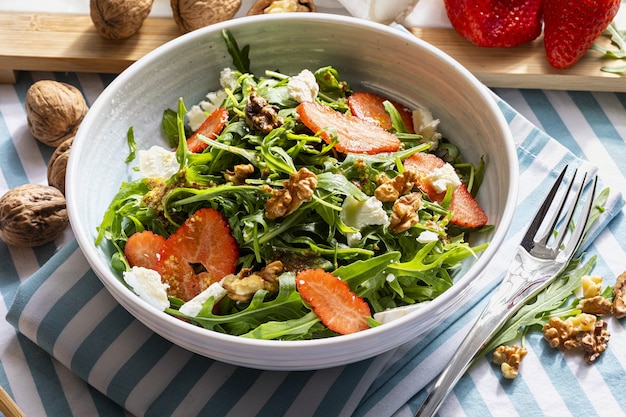 Vegetarischer und gesunder Salat aus grünen, natürlichen, rohen und frisch geschnittenen Rucola-Rgula-Sprossen und Blättern von Brassicaceae mit frischen Erdbeeren