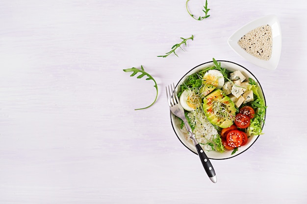 vegetarisches Buddha-Schüsselmittagessen mit Eiern, Reis, Tomate, Avocado und Blauschimmelkäse auf Tabelle.