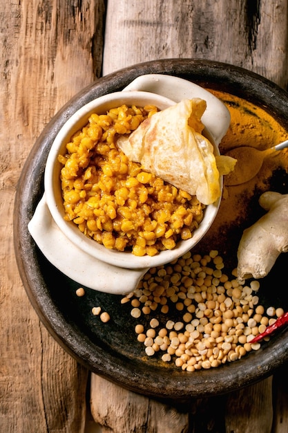 Vegetarisches Dhal mit Roti-Brot Traditionelles indisches veganes gelbes Erbsen-Dal mit Roti-Fladenbrot, serviert mit Zitrone in Keramikschale auf altem Holztisch Flacher Kopienraum