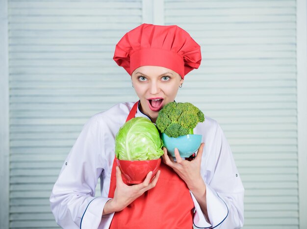 Vegetarisches Ernährungskonzept Diät- und Vitaminkulinarische Küche Glückliche Frau liebt gesundes Essen Bio- und vegetarische Köchin einheitliche professionelle Köchin, die in der Küche Brokkoli oder Kohl kocht