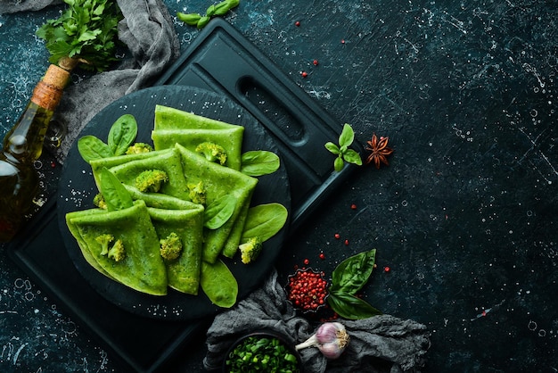 Vegetarisches essen grüne spinatpfannkuchen mit gemüse auf einer schwarzen steinplatte draufsicht freier platz für ihren text