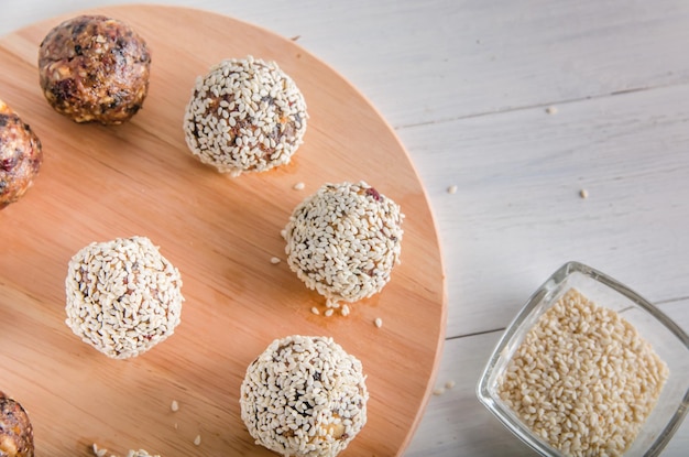 Vegetarisches Essen, hausgemachte Energiebällchen aus Walnüssen, Datteln, Pflaumen, Preiselbeeren und Honig mit Sesam auf weißem Hintergrund