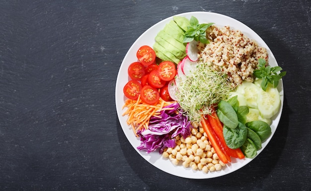 Vegetarisches Essen. Teller mit gesundem Salat mit Avocado, Quinoa, Tomate, Paprika, Spinat, Kohl, Sprossen und Kichererbsen, Ansicht von oben