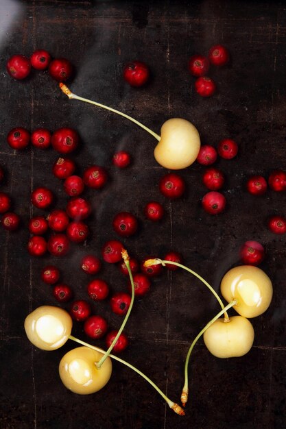 Vegetarisches Essenskonzept Süße saftige rote Johannisbeeren und gelbe Kirschen auf dunklem Hintergrund Ansicht von oben