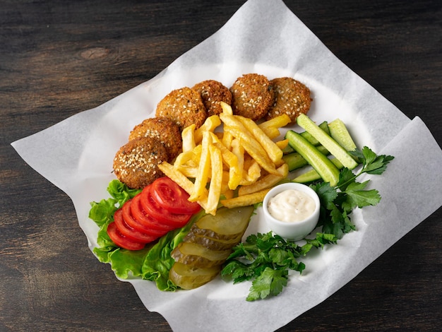 Vegetarisches Gericht Falafelbällchen mit Pommes Frites, frischem Gemüse und Soße Nahaufnahme