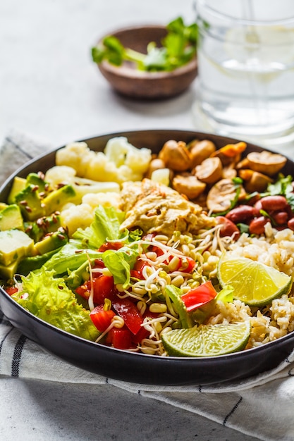 Vegetarisches Mittagessen. Naturreis mit Pilzen, Bohnen, Salat und Hummus im Schwarzblech, sauberes eatind.