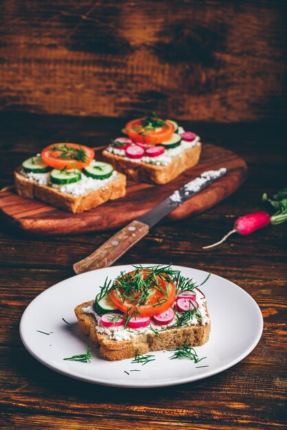 Foto vegetarisches sandwich mit frischen geschnittenen tomaten, gurke und rettich auf weißem teller