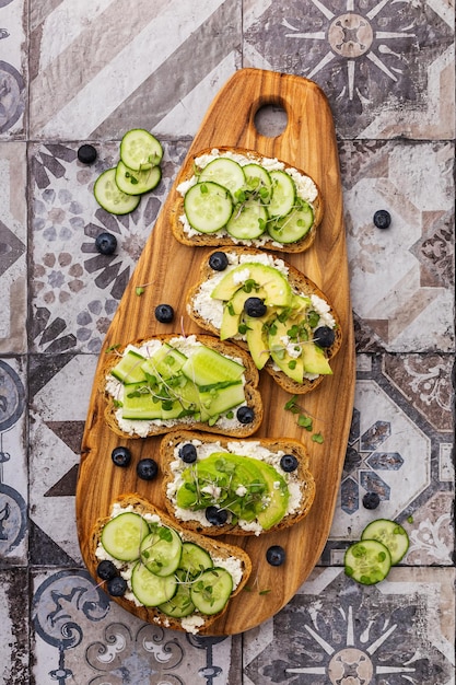 Vegetarisches Sandwich mit Microgreens auf einem Holzbrett, schöne Portion auf hellem Hintergrund