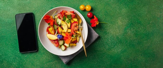 Foto veggie-sommersalat und smartphone auf grünem hintergrund