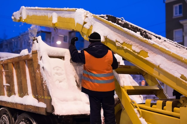 El vehículo con cargador de garra quita la nieve de la carretera La máquina quitanieves y el camión quitanieves limpian las calles