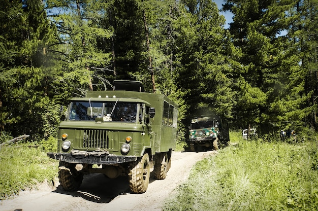 Vehículo militar en el bosque, viejos vehículos militares rusos circulando por un mal camino de tierra a través de la taiga