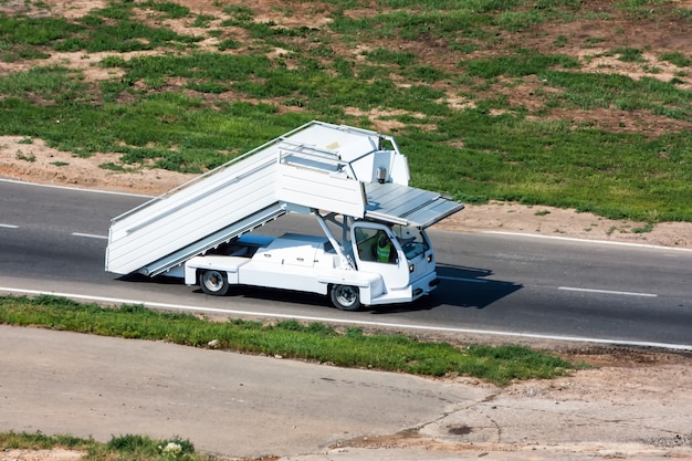 El vehículo de los pasos de embarque del pasajero se mueve en la carretera al aeropuerto