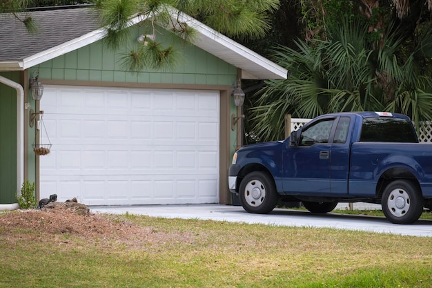 Veículo estacionado na frente de uma garagem larga de porta dupla na calçada pavimentada de uma típica casa americana contemporânea