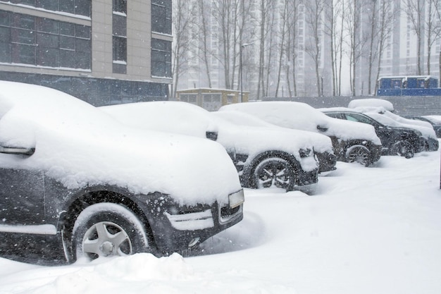 Veículos cobertos de neve na nevasca de inverno no estacionamento.