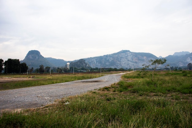 Veja o campo de grama da paisagem com a colina do vale da montanha e da vila no horário da manhã na cidade do distrito de Phra Phutthabat na província capital de Saraburi da Tailândia
