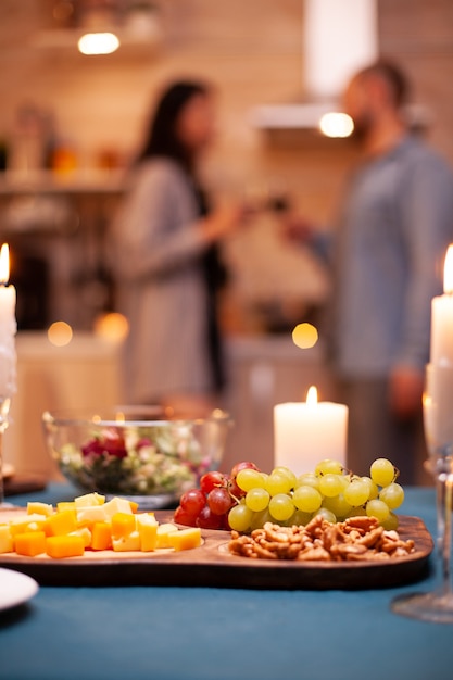 Foto vela acesa na mesa e close-up de uvas na mesa de madeira na cozinha enquanto o casal brindava.