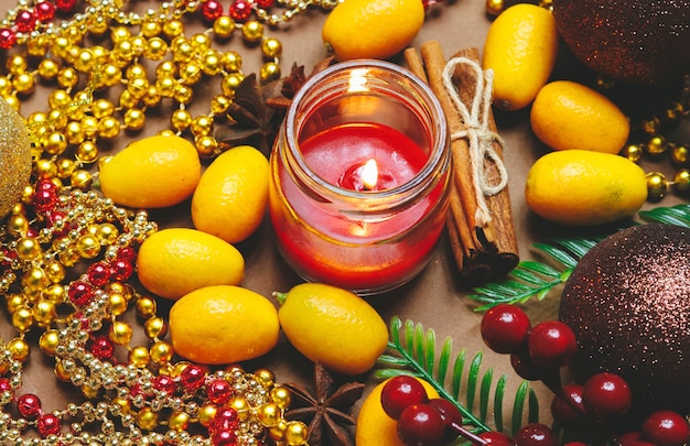 Foto vela, adornos navideños, canela y kumquat