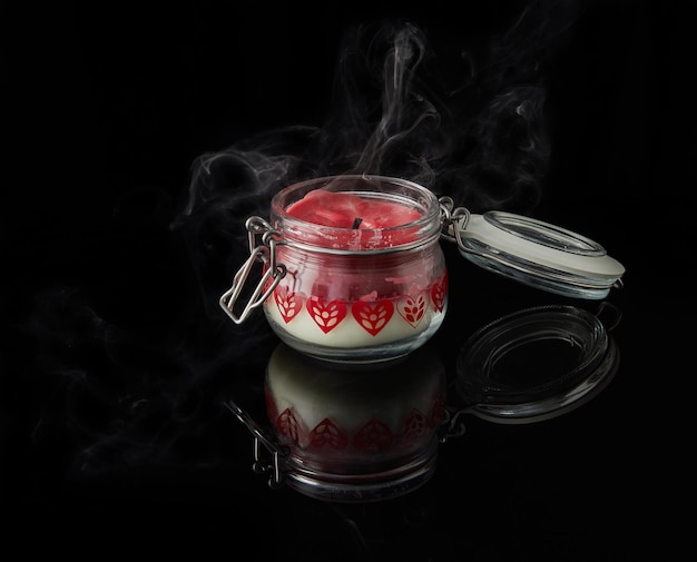 Una vela apagada con humo sobre fondo negro con aromas de granada de cereza vainilla y coco