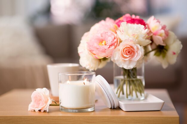 una vela ardiente y un ramo de flores en una mesa de madera