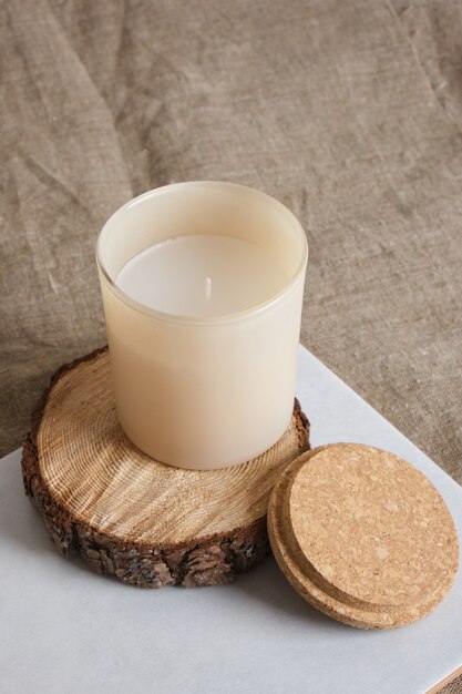 Vela de aroma beige en un podio de madera de una sierra cortada de un árbol. Velas naturales para aromaterapia copie el espacio.