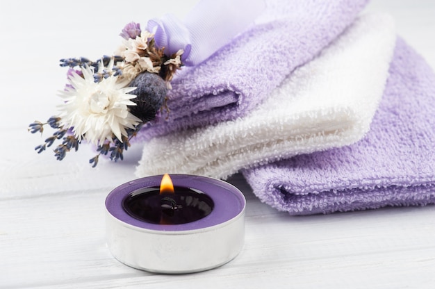 Vela aromática, toallas de color púrpura y lavanda en primer plano de arreglo de spa