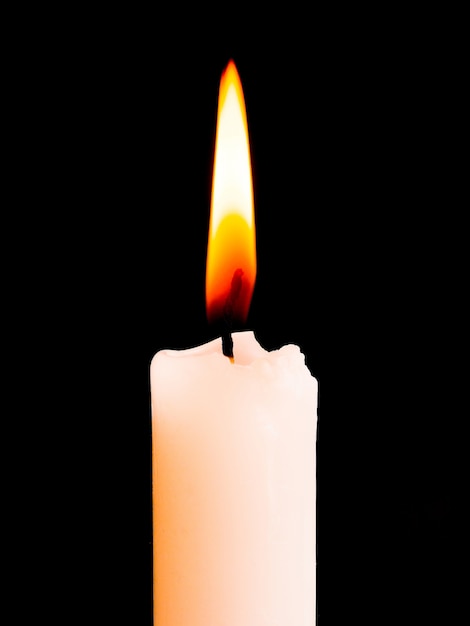 Una vela blanca arde brillantemente sobre un fondo negro aislado