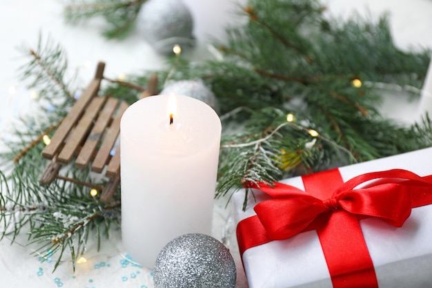 Vela brilhante com decoração de natal e presente na superfície branca