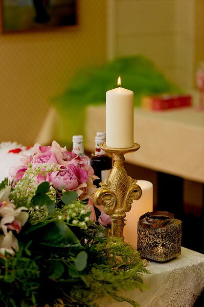 Vela en un candelabro de oro sobre la mesa de los recién casadosFloristería de bodas