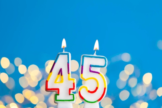 Vela de celebración de cumpleaños número 45 contra luces brillantes y fondo azul