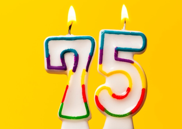 Foto vela de celebración de cumpleaños número 75 contra un fondo amarillo brillante