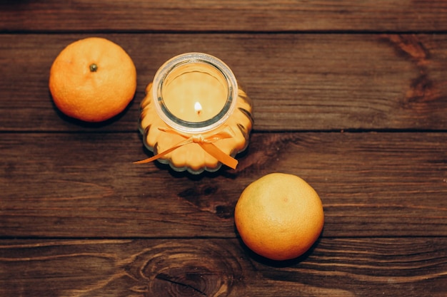 Vela de cera y naranja aromática en un candelabro sobre una mesa de madera