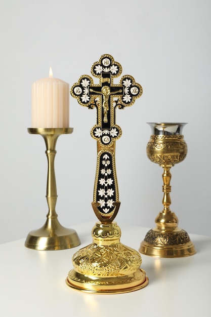 Vela copo dourado e cruz na mesa sobre fundo branco