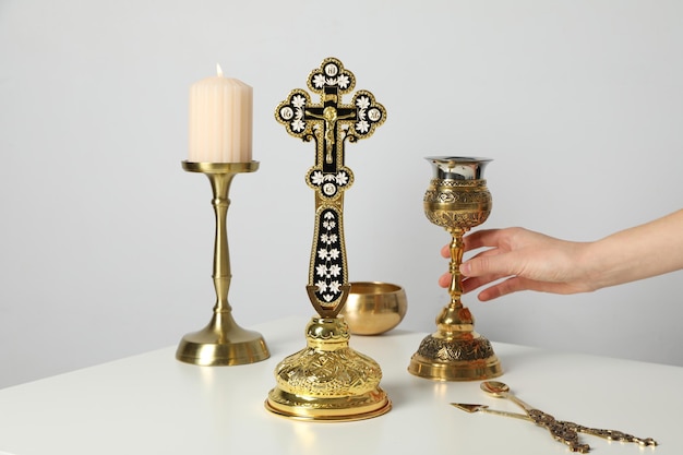 Vela copo dourado na mão e cruz na mesa sobre fundo branco